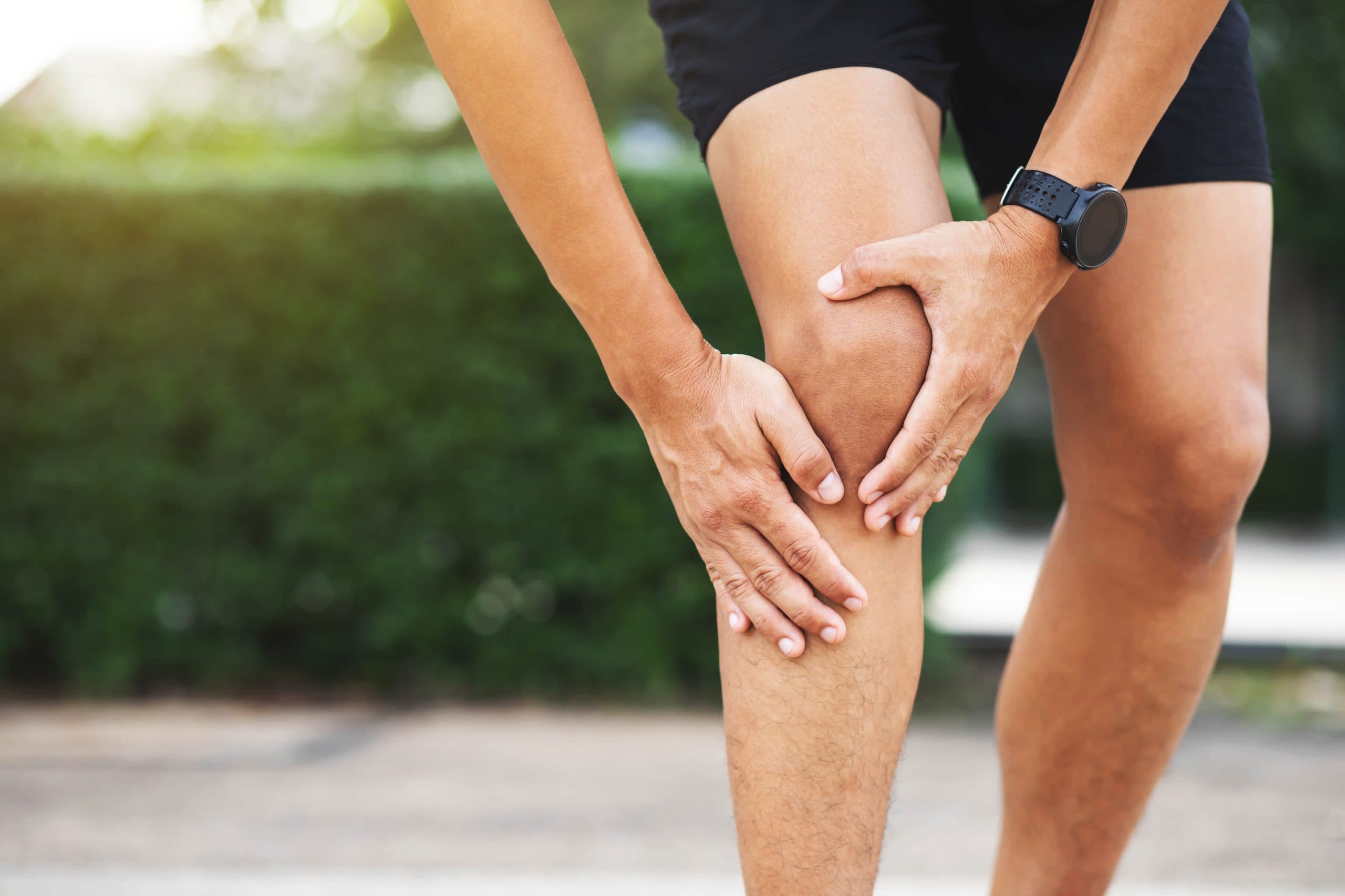 Runner gripping the side of the knee outdoors